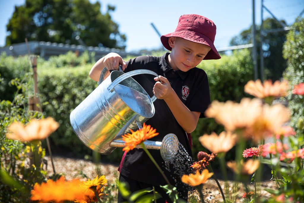 student watering flowers in garden