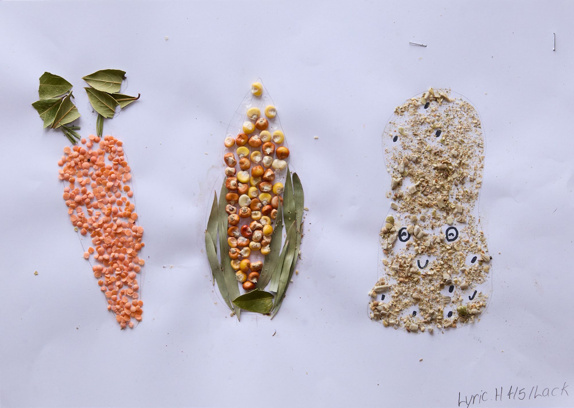An art piece showing a carrot, corn, and a smiling peanut made from seeds, lentils, and leaves on white paper. Whimsical and creative.