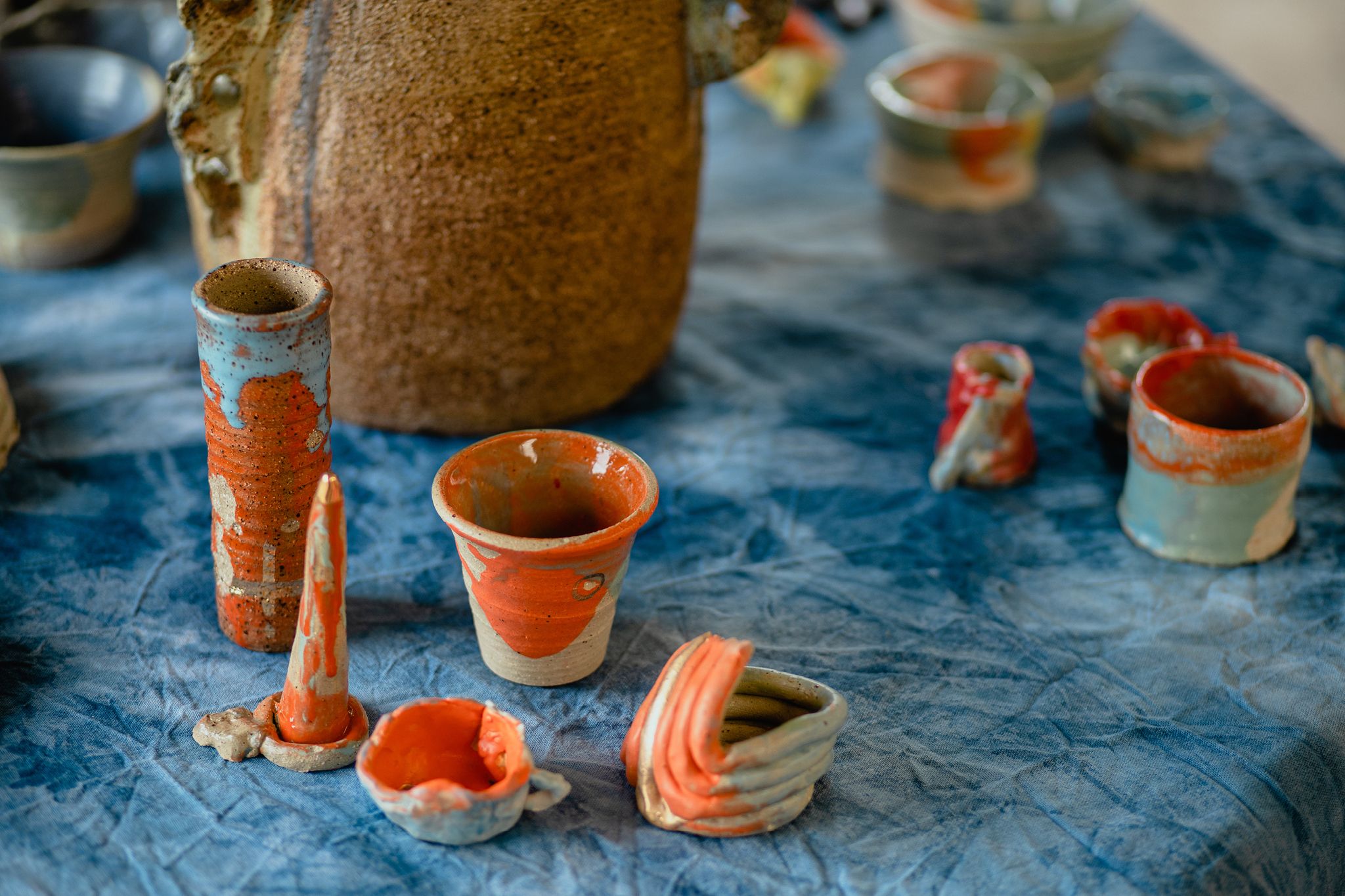 a table topped with orange and white vases and cups