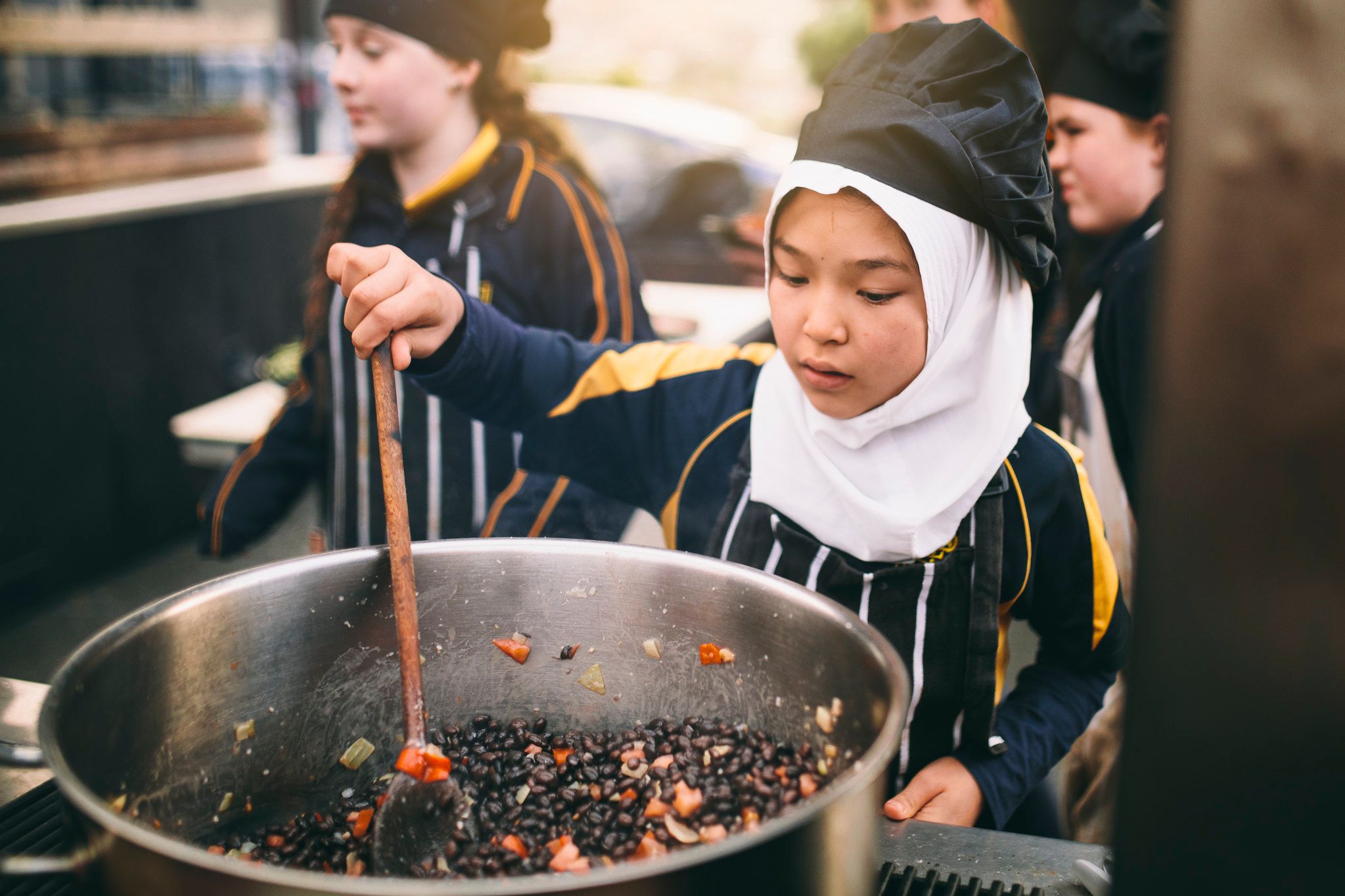 People serving themselves fresh vegetable dishes in a communal table setting